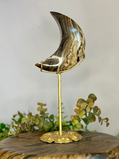 Chocolate Calcite crescent moon crystal with natural brown and caramel banding displayed on a decorative gold stand.