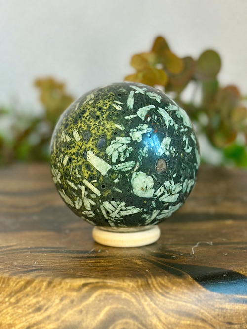 Chrysanthemum Stone crystal sphere with pale flower-like formations across a dark green matrix