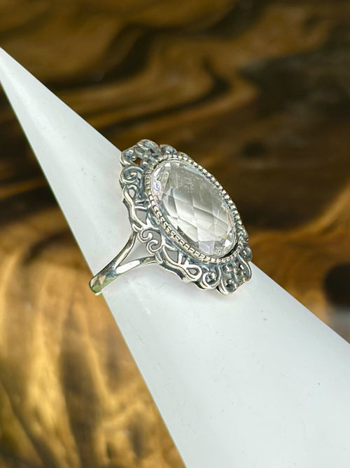 Side view of faceted Clear Quartz ring with ornate scrollwork setting