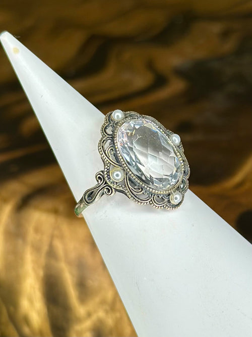 Side view of oval Clear Quartz crystal ring with pearl-style accents