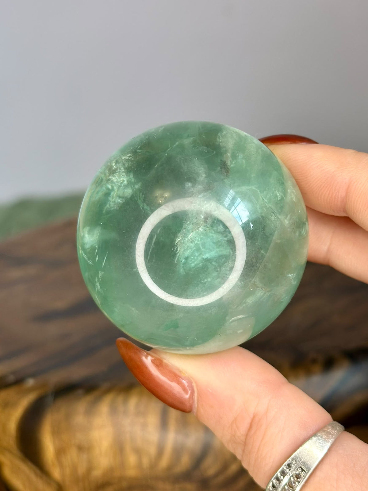Polished Green Fluorite crystal sphere showing natural internal patterns and green tones
