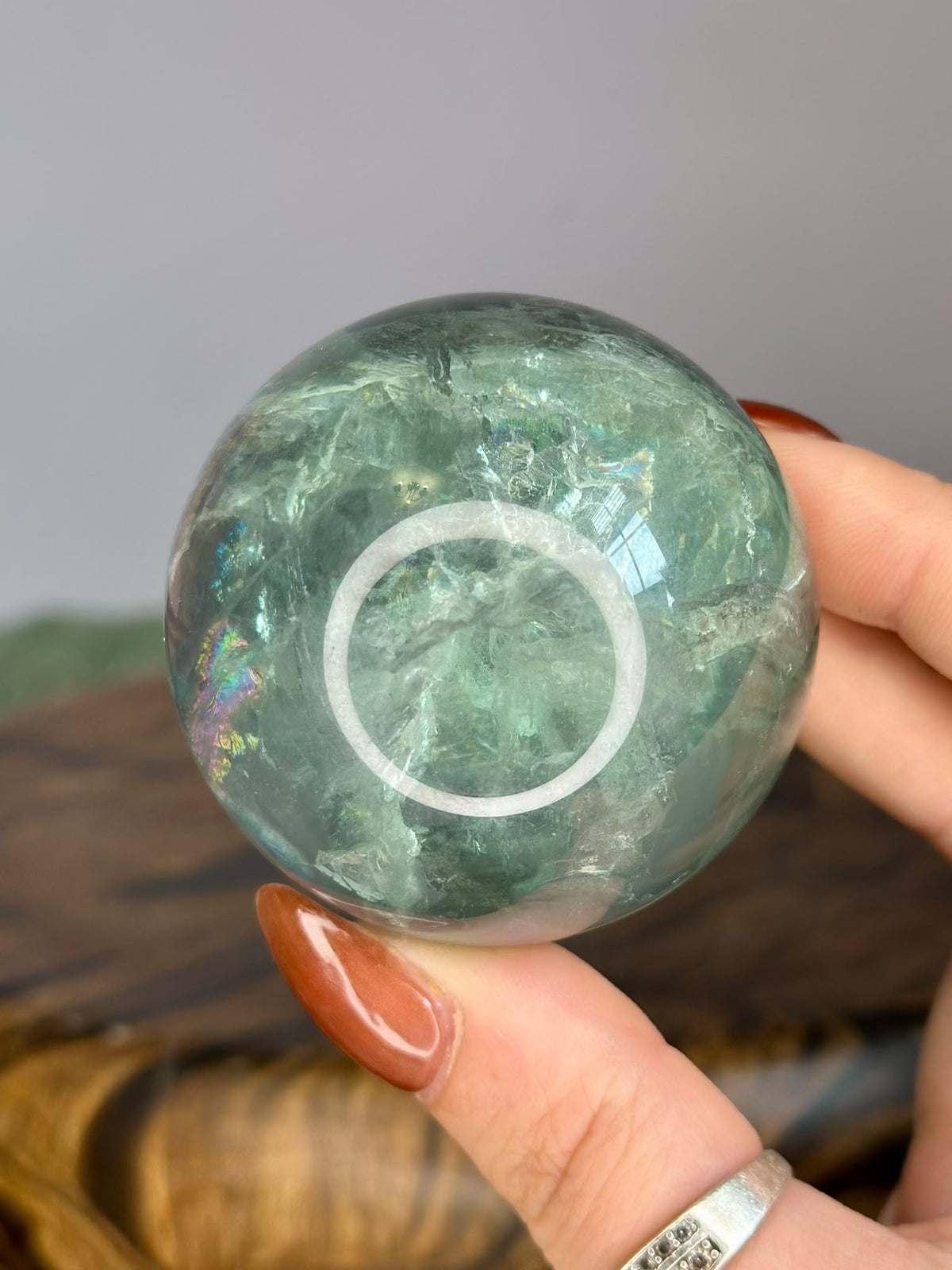 Polished Green Fluorite sphere showing internal rainbow flashes and natural inclusions