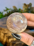 Polished 117g Sunstone Moonstone sphere showing warm champagne tones, natural internal texture and subtle blue flash